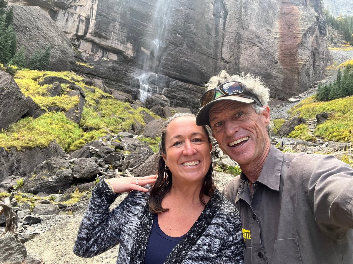 a man and a woman standing in front of a large rock