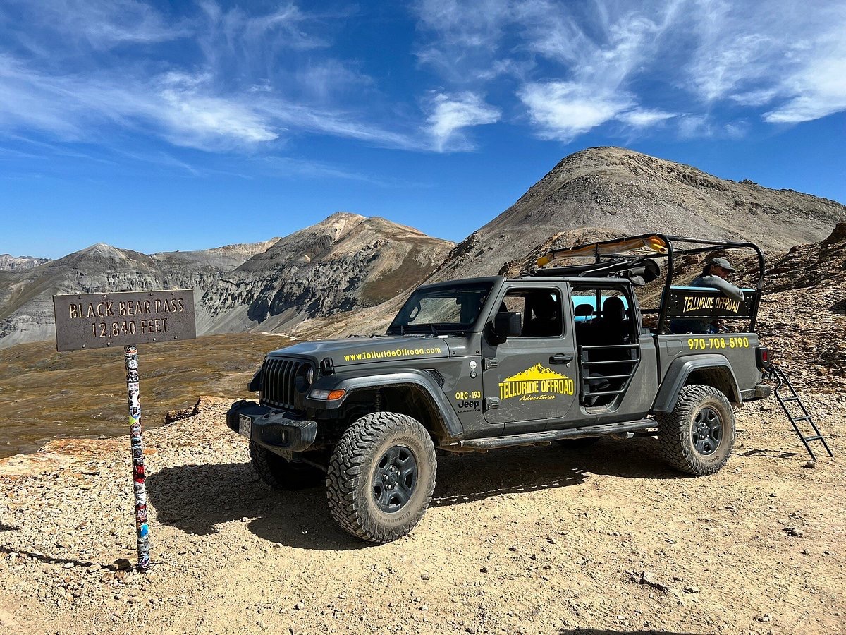 a truck driving down a dirt road with Old Trail Town in the background